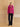 Full-length front view of the Glow Pink cashmere bomber jacket with fur collar, paired with dark wide-leg denim and black pointed boots.