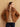 Front view of the Warm Camel cashmere bomber jacket with fur collar, worn open over a camel sweater and dark denim.