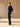 Full-length three-quarter back view of the Midnight Navy Donegal cashmere sweater, paired with dark wide-leg denim and brown boots.