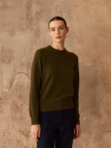 Front view of the Classic Cashmere Crewneck Sweater in Olive, showing its long sleeves and hip-length fit over dark denim.
