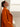 Close side view of the Burnt Pumpkin cashmere wrap coat, showing the collar, shoulder and soft drape over an ivory top.