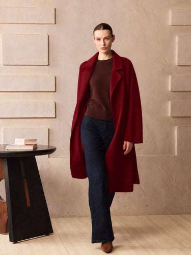 Full-length front view of the Deep Burgundy Classic Cashmere Wrap Coat, worn open over a brown sweater and dark wide-leg denim.