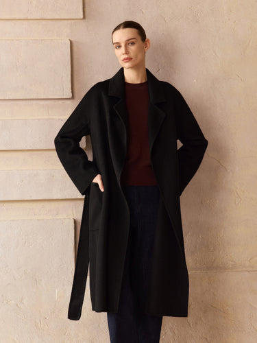 Model wearing the Classic Cashmere Wrap Coat in Jet Black open over a burgundy sweater and dark denim, front view.