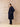 Full-length three-quarter side view of the Midnight Navy cashmere wrap coat, worn open with one hand in a side pocket.