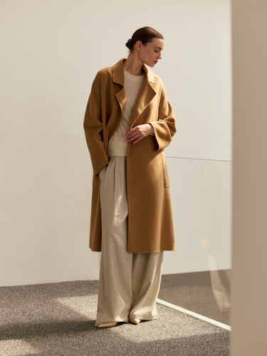 Model wearing the Classic Cashmere Wrap Coat in Warm Camel open over ivory knitwear and wide-leg trousers, full-length front view.