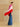 Full-length side view of the Rose Multi cashmere topper, showing bright pink, pale pink and red panels flowing over blue wide-leg denim.