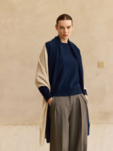 Front view of the Midnight Navy and Beige Donegal cashmere travel wrap draped over a navy sweater and grey trousers.