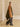 Model walking with the Olive and Deep Chestnut cashmere travel wrap draped over the shoulders, showing its long panels and contrast trim.