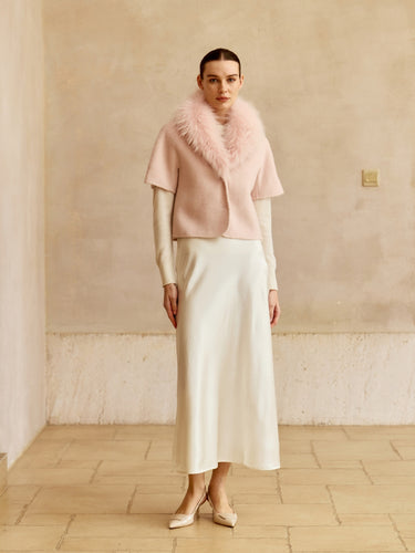 Full-length front view of the Blush short-sleeve cashmere jacket with matching fur collar, styled with an ivory midi skirt and heels.