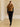 Model walking in the Camel short-sleeve cashmere jacket with fur collar, paired with black trousers and heeled sandals.