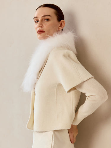Side view of the Soft Ivory cashmere jacket, showing the fur collar, short sleeves and rounded front edge.