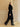 Model walking in the Jet Black Signature Cashmere Wrap Coat with fur collar, paired with black leather trousers and pointed shoes.