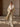 Model walking in the Soft Ecru Signature Cashmere Wrap Coat with white fur collar, holding the open front over tonal knitwear and trousers.