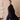 Model wearing a black wrap coat open over a burgundy sweater and dark blue jeans, with one hand in the coat pocket.