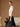 Side view of the Soft Ivory brushed cashmere sweater, showing its short sleeves and gently skimming fit over a black satin skirt.
