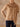Close-up of the Almond cashmere sweater, showing the matching scarf’s fringe trim and the sweater’s ribbed cuffs and hem.