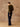 Full-length three-quarter back view of the Olive cashmere crewneck sweater, paired with dark wide-leg denim and brown boots.