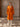 Full-length front view of the Burnt Pumpkin cashmere wrap coat, belted over ivory wide-leg trousers.