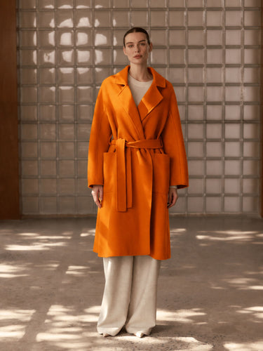Full-length front view of the Burnt Pumpkin cashmere wrap coat, belted over ivory wide-leg trousers.