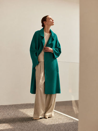 Full-length view of the Emerald Green cashmere wrap coat, worn open over an ivory top and wide-leg trousers.
