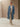Model walking in the Classic Cashmere Wrap Coat in Powder Blue, worn open over an ivory sweater and wide-leg trousers.