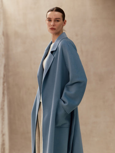 Closer three-quarter view of the Classic Cashmere Wrap Coat in Powder Blue, showing the notched lapels and generous sleeves.