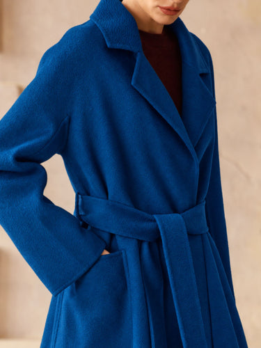 Close-up of the Royal Blue cashmere wrap coat, showing the notched lapels, self-tie belt, side pocket and stitching along the cuff.