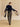 Full-length back view of the Navy and Beige Donegal cashmere travel wrap worn low around the arms, with both ends held outward.