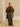 Full-length front view of the Olive and Deep Chestnut cashmere travel wrap styled over a matching olive sweater and grey trousers.