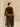 Back view of the Olive and Deep Chestnut cashmere travel wrap worn low around the arms, with both ends hanging behind the model.