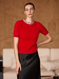 Front view of the Ruby Red brushed cashmere short-sleeve sweater with a jeweled crew neckline, worn with a black satin skirt.