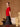 Side view of the Ruby Red short-sleeve cashmere sweater, showing its gently skimming fit and ribbed hem above a black satin skirt.