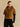 Front view of the Camel short-sleeve cashmere jacket with matching fur collar, worn over a black top and trousers.