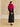 Full-length back view of the Glow Pink cashmere jacket with fur collar, worn with a black satin midi skirt and heeled sandals.