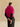 Back view of the Glow Pink short-sleeve cashmere jacket, showing the fur collar and compact silhouette over a black top.