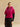 Front view of the Glow Pink short-sleeve cashmere jacket with matching fur collar, worn over a black top and satin skirt.